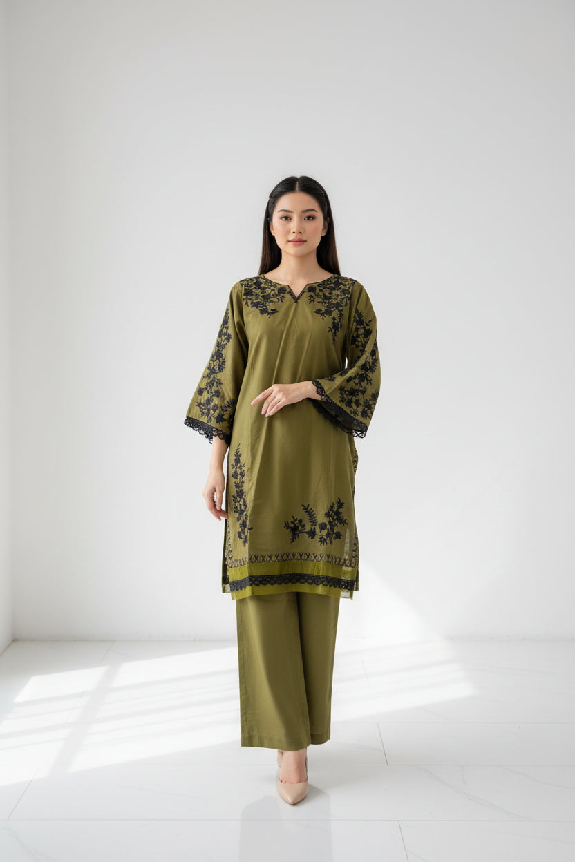 Green dress with black floral embroidery on a mannequin in a store setting.